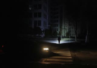 A pedestrian uses a flashlight to cross the road